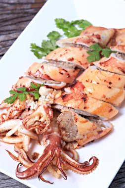 Sarımsaklı ve domuzlu ızgara kalamar. Tayland tarzı beyaz tabakta izole