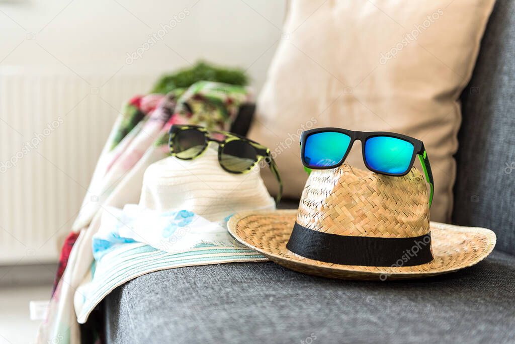 Holiday and vacation concept.  Straw hat and sunglasses on the sofa. Blurred background. 