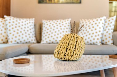 Oturma odası elemanı. Masanın üzerinde ananas şeklinde dekorasyon var. Arka planda dekoratif yastıklı kanepe. 