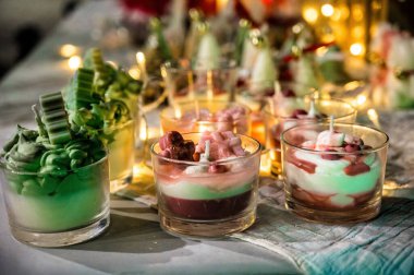 Noel tatlısı şeklinde dekoratif tatil mumları, festival masasında parlayan sıcak ışıklar, sıcak kış atmosferi, Noel ve yeni yıl için sezonluk dekor konsepti