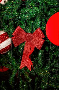 Noel ağacı süslemelerini parlak kırmızı kurdele ve yeşil dallardaki balo süslemeleri, bayram dekorları, kış kutlaması arka planı, mevsimlik süslemeleri ile kapat.