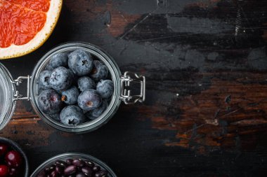 Cam kavanozda olgun yaban mersini, düz, koyu ahşap zemin üzerinde, metin için yer var..