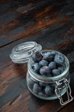 Eski ahşap arka planda cam kavanozda olgun yabanmersini..