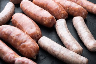 Taze çiğ domuz eti, sığır eti ve tavuk sosisi, siyah arka planda..