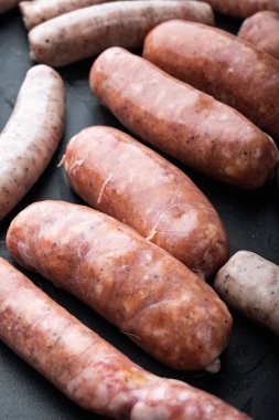 Taze çiğ domuz eti, sığır eti ve tavuk sosisi, siyah arka planda..