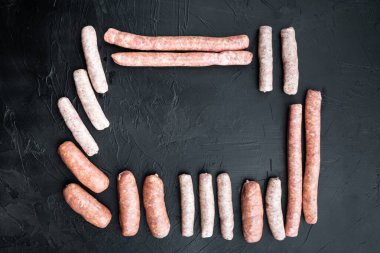 Çiğ sosisler seti, çerçeve veya sınır kavramı, üst görünümü metin için alan, siyah arkaplan üzerine.