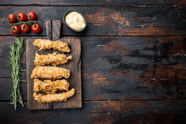 Crispy chicken sticks meat on dark wooden background, top view, with space for text.