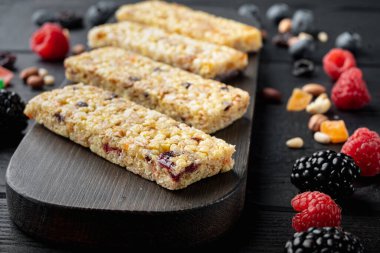 Kuru üzüm ve böğürtlenli granola bar, siyah ahşap masa üzerinde.