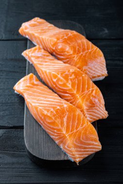 Çiğ somon filetosu, siyah ahşap masada.