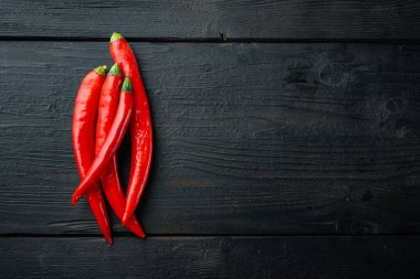 Çiğ kırmızı biber seti, siyah ahşap masa üzerinde, düzlük ve metin için boşluk.