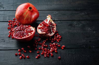 Sulu tohumlarla dolu olgun nar, siyah ahşap masa üzerinde metin için yer var.