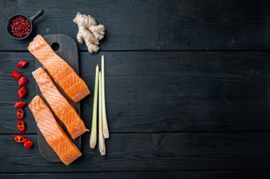 Somon otları ve baharatlarla dolu balık köfteleri, siyah ahşap masa üzerinde, düz yerde metin için yer var.