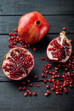 Sulu tohumlarla dolu olgun nar, siyah ahşap masa üzerinde.