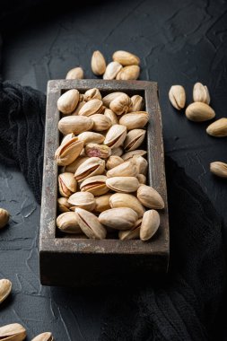 Kabuklu, tuzsuz, siyah desenli arka planda fıstıklar.