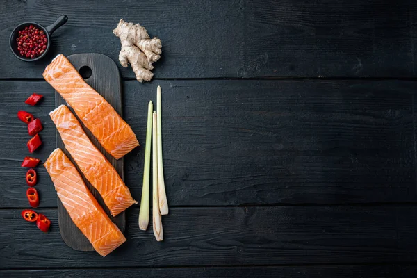 Somon otları ve baharatlarla dolu balık köfteleri, siyah ahşap masa üzerinde, düz yerde metin için yer var.
