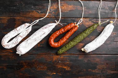 İspanyol salamı, fuet ve sucuklu sosisler eski ahşap masa üzerinde, üst görünümü metin için alan.