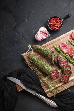 İspanyol fuet salam sosisi dilimleri siyah desenli arka planda.