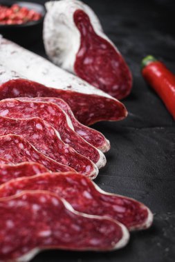 İspanyol Longaniza salam sosisi siyah desenli arka planda otlarla dilimler.