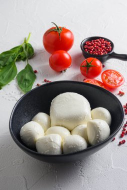 Siyah kasede Mozzarella peyniri, fesleğen domates kiraz balzamik siyah kayrak taşı fotokopi alanı. Beyaz arkaplan üzerindeki Caprese salatası içeriği vselektif odak dikey kapat.