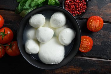 Siyah kâse içinde Mozzarella peynirli bufalo topları eski ahşap tahtaların üzerinde tepeden görünüyor..