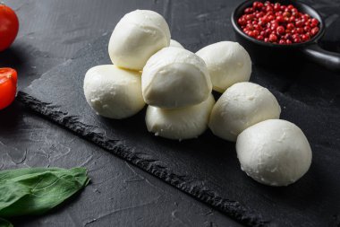 Mozzarella peyniri, fesleğen domates vişneli siyah arka planda siyah taş levha..
