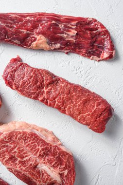 Çiğ Denver, pala bifteğinin yanında beyaz arka planda mermer biftek. Yakın plan..