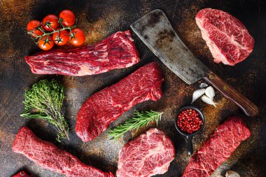 Farklı türde çiğ biftek, kasap bıçağı ile rustik metall üst görünüm düz yatıyordu.