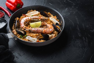 Kral karidesli Valenciana paella, siyah arka planda midye ve kalamar, yemek fotoğrafı..