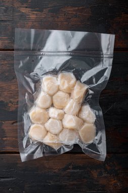 Vakum paketinde donmuş et midyeleri, düz yerde, koyu ahşap arka planda.