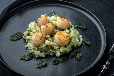 Izgara deniz tarağı ve patates püresi, siyah desenli arka plan.