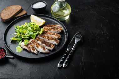 Kırılmış, ızgarada tavuk göğsü filetosu, siyah arkaplanda metin için yer var.