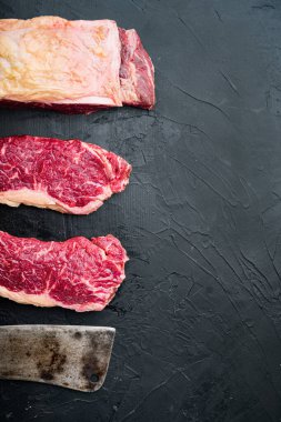 Striploin bifteği, çiğ et kasabı kesimi, siyah arkaplan, üst görünüm, metin için kopyalama alanı