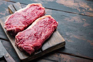 Ham Büyükelçi bifteği kesilmiş, koyu ahşap arka planda, metin için kopyalama alanı var.