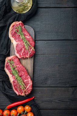 Strip fileto biftek, çiğ mermer et, siyah ahşap masa, üst görünüm, metin için fotokopi alanı