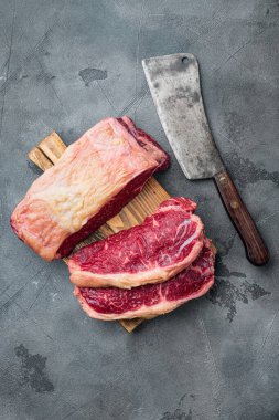Gri arka planda kesilmiş sığır filetosu biftekleri.