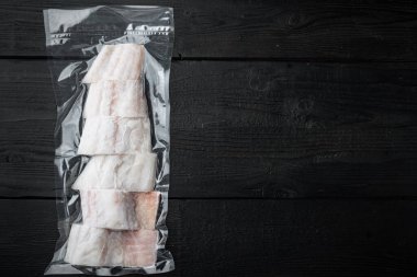 Çiğ mezgit balığı derisiz plastik vakum paketi, siyah ahşap arka planda, metin için metin alanı ile üst görünüm