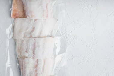 Beyaz mezgit balığı filetosu plastik pazar paketinde, beyaz arkaplanda, metin için metin alanı ile üst görünüm
