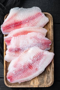 Donmuş çiğ tilapia balığı eti, eski ahşap masa, üst manzara