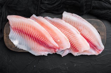 Çiğ beyaz balık fileto kesimleri, siyah arkaplan, üst görünüm