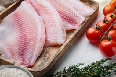 Beyaz balıklı fileto, pirinçli ve kirazlı domatesli beyaz arka planda.