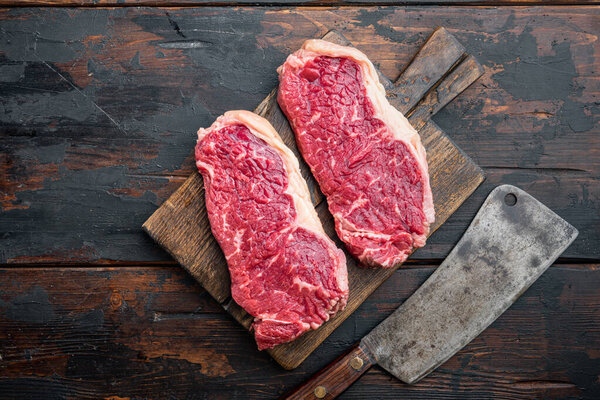 Sirloin steak, uncooked beef meat cut, on dark wooden background, top view, with copy space for text