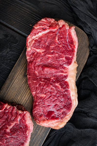 Fresh beef boneless club raw steak, on black wooden background, top view