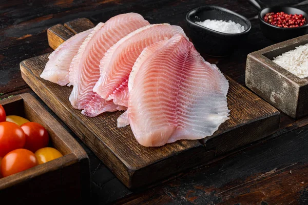 White fish fillet, with basmati rice and cherry tomatoes ingredients, on old wooden table