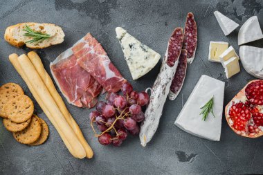 Farklı antipasti setiyle aperatifler masası, gri arka planda, düz uzanmış