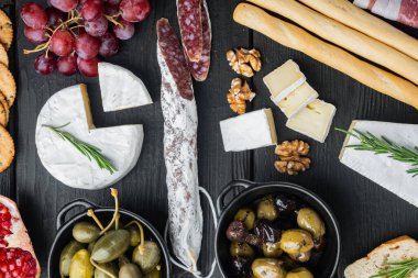 Taze peynirli, ekmekli ve zeytinli antipasti tabağı, siyah ahşap masa, üst manzara.