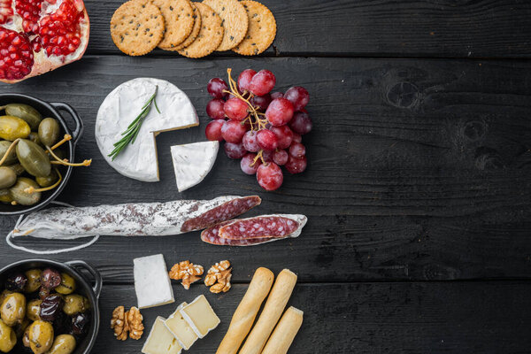 Spanish snacks, meat cheese, herbs set, on black wooden table, top view  with copy space for text