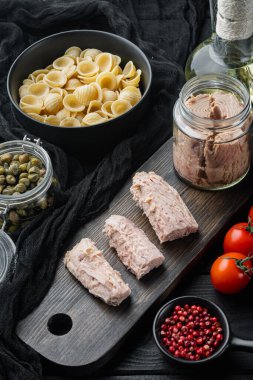 Sicilya ton balıklı makarna malzemesi, siyah ahşap arka planda.