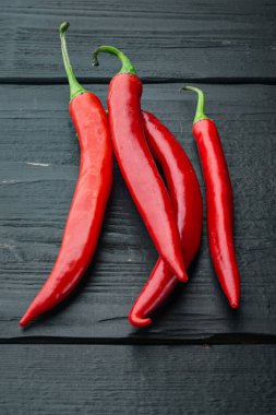 Siyah ahşap arka planda kırmızı biber seti.