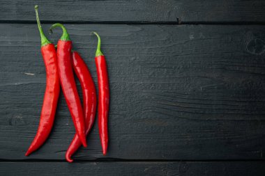 Olgun kırmızı biber seti, siyah ahşap arkaplan, üst görünüm veya düz metin için metin alanı ile yatar