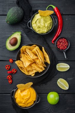 Üçgen sarı mısır tortilla soslu, siyah ahşap arka planda, üst ya da düz yatar